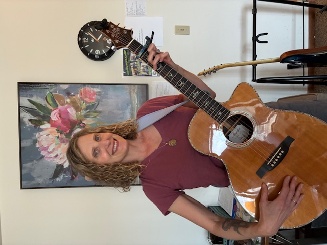 A portrait of Heather Rabata holding a guitar.